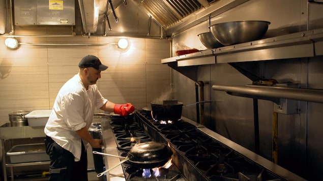Photo d'un cuisinier devant son poêle.