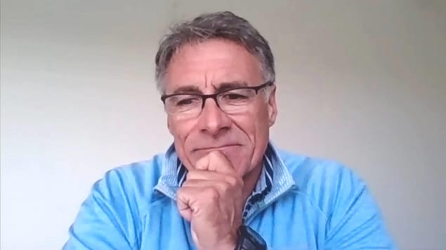 Allister Surette devant une webcam, le menton appuyé sur sa main.