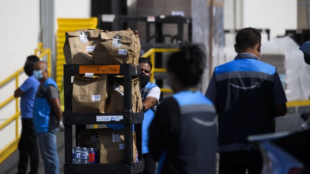 Des employés à l'extérieur d'une installation de distribution d’Amazon.