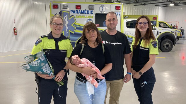 Deux ambulancières entourent un couple avec un bébé.
