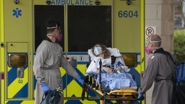Deux ambulanciers et une dame couchée sur une civière.