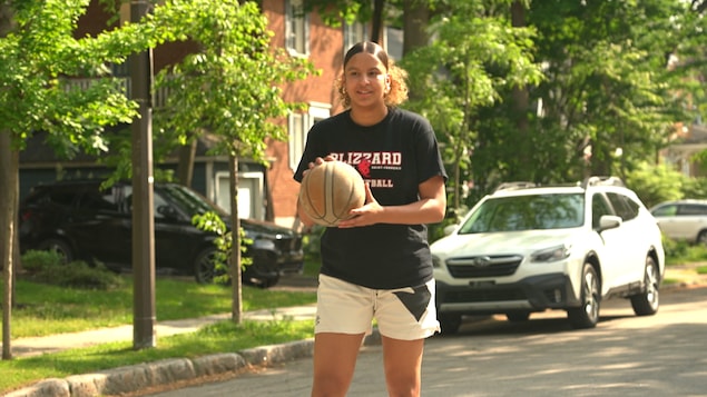 Une adolescente joue au basketball dans un quartier résidentiel.