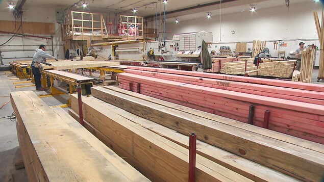 Un travailleur s'affaire au-dessus de planches de bois dans l'usine de l'entreprise AmeriCan Structures.