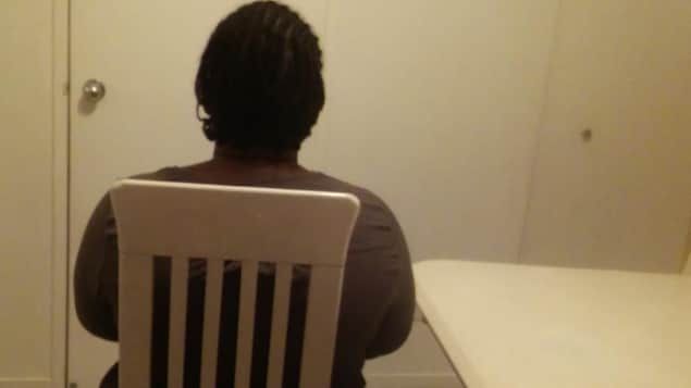 La femme assise sur une chaise, de dos.