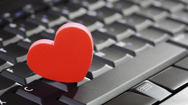 Un cœur rouge posé sur un clavier d'ordinateur. 