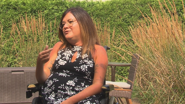 Une dame est assise dans un fauteuil roulant à l'extérieur.