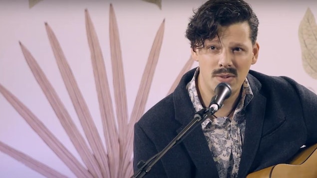 L'auteur-compositeur-interprète André Péloquin-Hopfner devant un micro avec sa guitare
