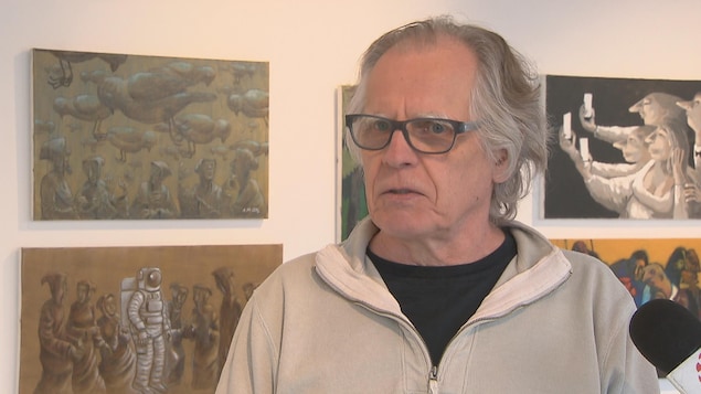 Un homme répond aux questions d'une journaliste dans une galerie de Québec où ses oeuvres sont exposées.