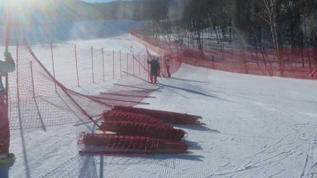 Des bénévoles installent des clôtures rouges le long d’une piste de ski. Des bénévoles installent des clôtures rouges le long d’une piste de ski.
