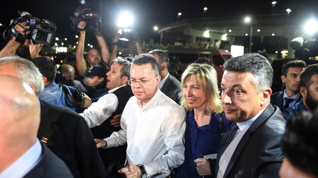 Entouré de médias et de gardes de sécurité, le pasteur américain Andrew Brunson se déplace vers l'aéroport d'Izmir, en Turquie. Entouré de médias et de gardes de sécurité, le pasteur américain Andrew Brunson se déplace vers l'aéroport d'Izmir, en Turquie.