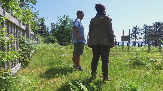 Andy Wilson et la journaliste se tiennent devant les stèles dans le cimetière. Andy Wilson et la journaliste se tiennent devant les stèles dans le cimetière.