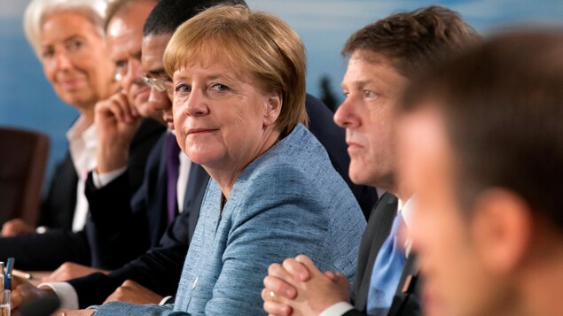 Angela Merkel est assise à une table avec d'autres personnes. Angela Merkel est assise à une table avec d'autres personnes.
