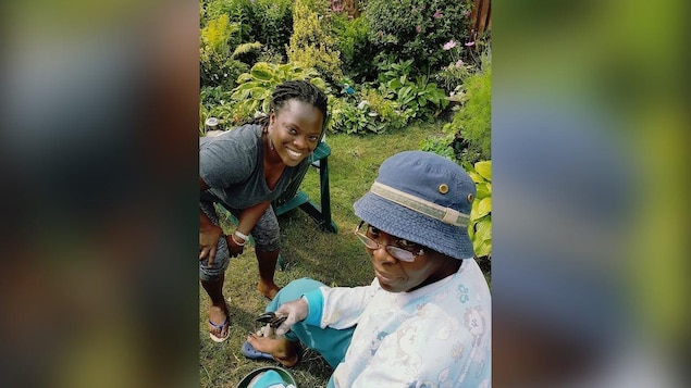 A woman leans in for a picture with an elderly woman sitting down.
