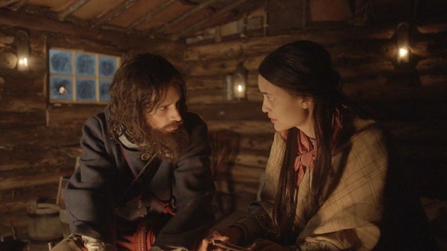 Une femme autochtone et un homme barbu se regardent dans les yeux dans une cabane de bois. Une femme autochtone et un homme barbu se regardent dans les yeux dans une cabane de bois.