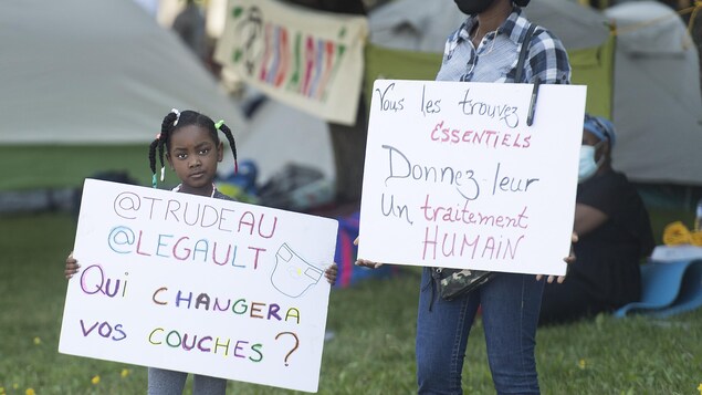 Une petite fille tient une pancarte sur laquelle il est écrit : « Trudeau, Legault, qui changera vos couches? »