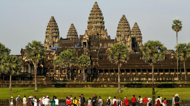 Des touristes en avant-plan regardent le site archéologique Angkor, au Cambodge. 
