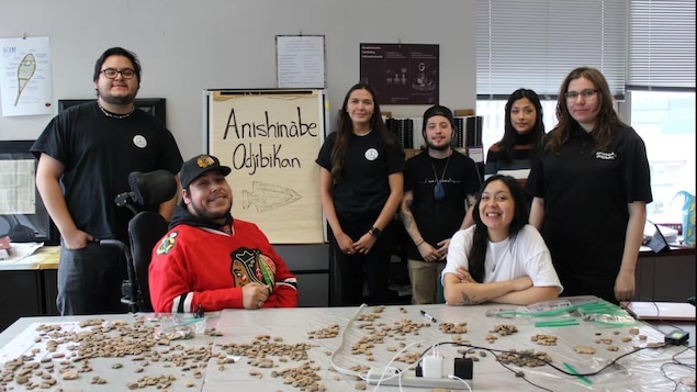 Des jeunes posent pour la photo dans une salle de classe avec des artefacts étalés sur la table.