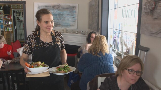 On voit Mme Martin dans son restaurant, en train d'apporter des plats aux clients. On voit Mme Martin dans son restaurant, en train d'apporter des plats aux clients.