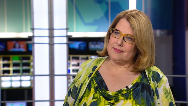 Me Anne-France Goldwater, portant une haut vert et des lunettes jaunes et noires.