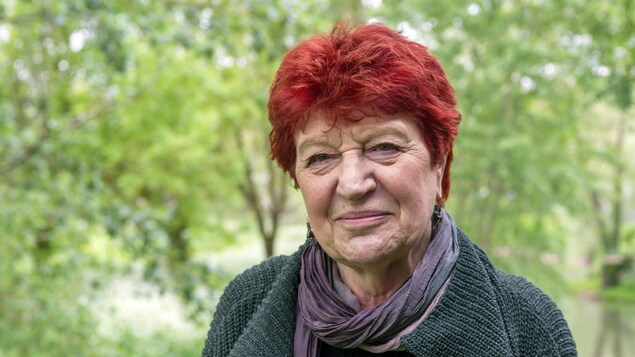 La femme prend la pose pour la caméra devant des arbres.