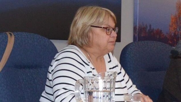 Une femme avec des lunettes assise.