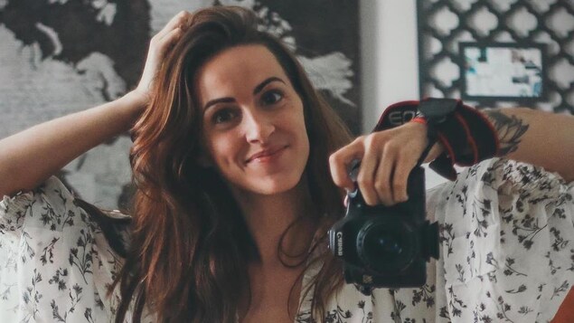 Une jeune femme assise en tailleur se prend en photo dans le miroir.