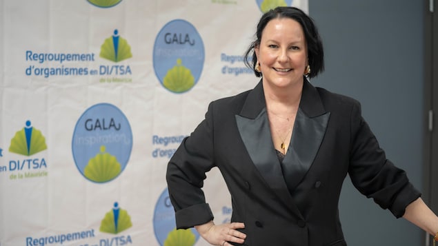 Une femme est debout et sourit à la caméra.