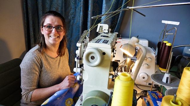 Annie Larocque sourit, assise devant une machine à coudre.