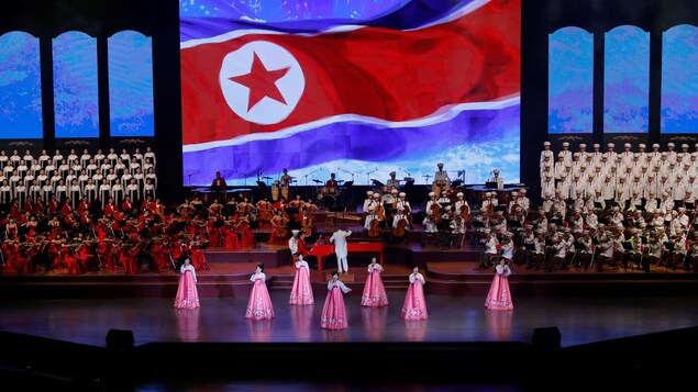 Une scène sur laquelle ont voit des chanteuses. En arrière-plan, un orchestre et le drapeau nord-coréen. Une scène sur laquelle ont voit des chanteuses. En arrière-plan, un orchestre et le drapeau nord-coréen.