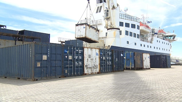 La grue décharge des conteneurs du navire Bella-Desgagné vers le quai de Port-Menier sur l'île d'Anticosti, on aperçoit aussi derrière la passerelle pour les passagers. La grue décharge des conteneurs du navire Bella-Desgagné vers le quai de Port-Menier sur l'île d'Anticosti, on aperçoit aussi derrière la passerelle pour les passagers.