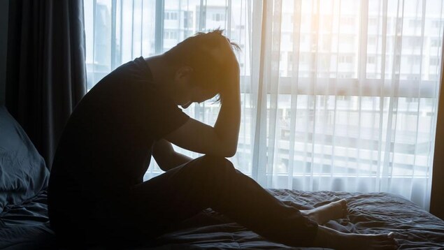 Un homme dans son lit se tient la tête