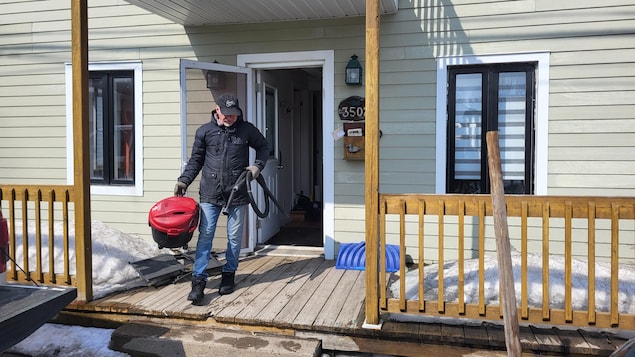 Un homme sort une balayeuse d'un logement.