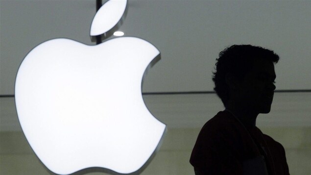 The shadow of a man's profile in front of the apple logo of Apple.