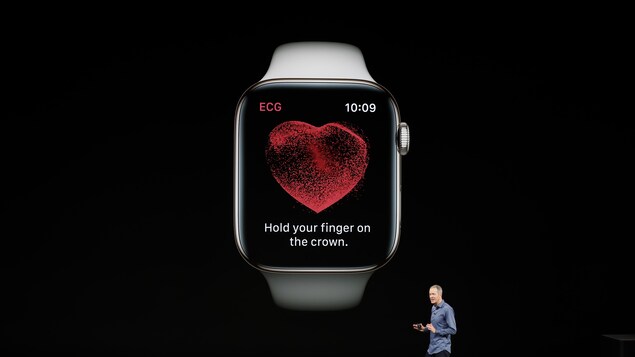 Une photo de l'Apple Watch sur un écran géant. Un homme se tient devant l'écran. Une photo de l'Apple Watch sur un écran géant. Un homme se tient devant l'écran.