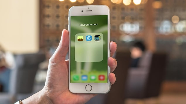 Trois applis écolo sur un écran de iPhone dans un café.