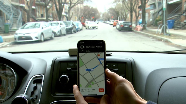Le passager d’une voiture tient dans sa main gauche un téléphone portable sur lequel l’application Espace Park a été installée.