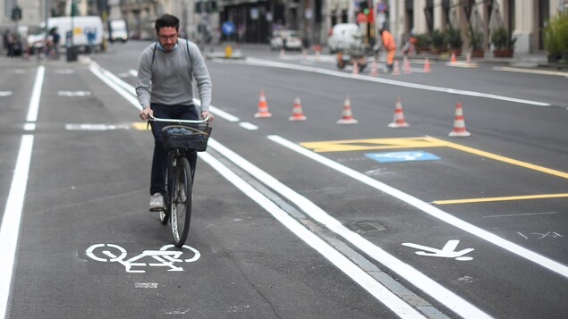 Un homme roule à vélo sur une piste cyclable dans une ville italienne.