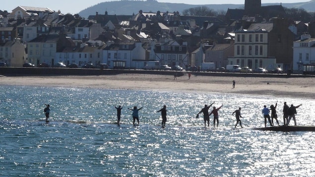 Beachgoers walk along a tidal causeway in the town of Peel on the Isle of Man on Monday, March 26, 2012.