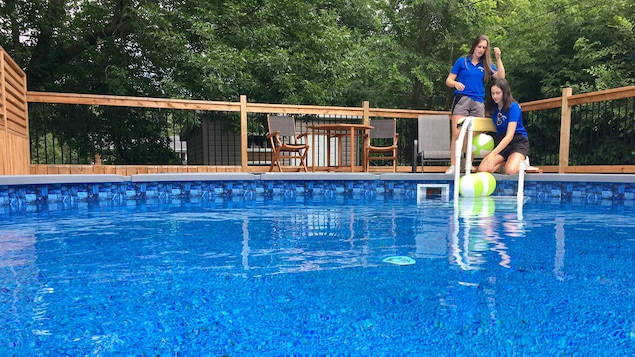 Deux jeunes qui sont tout près d'une piscine.