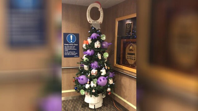 Un sapin décoré avec un siège de toilette et des gants médicaux gonflés.