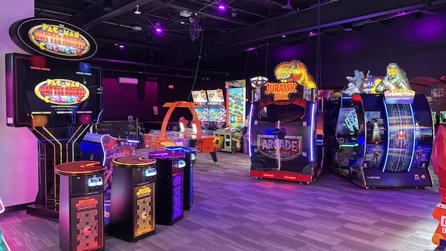 Des arcades illuminées présentant des jeux tels que Pac-Man.