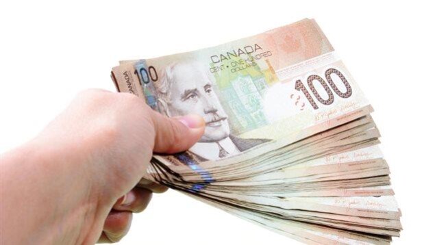 Une main tenant une liasse de billets de 100 $