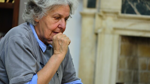 Ariane Mnouchkine, fondatrice du Théâtre du Soleil, regarde vers le sol, tenant son menton dans sa main.