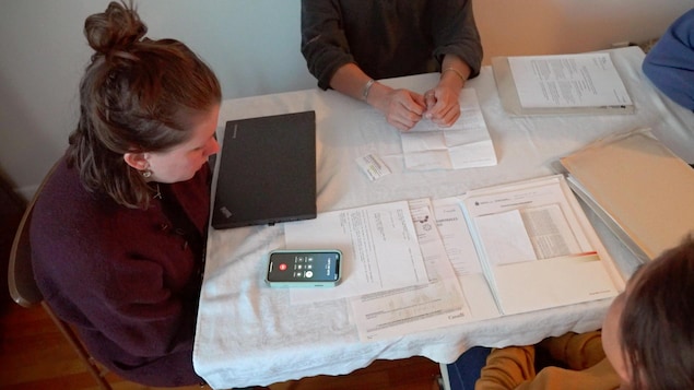 Quatre personnes assises autour d’une table où il y a plusieurs documents et un téléphone.