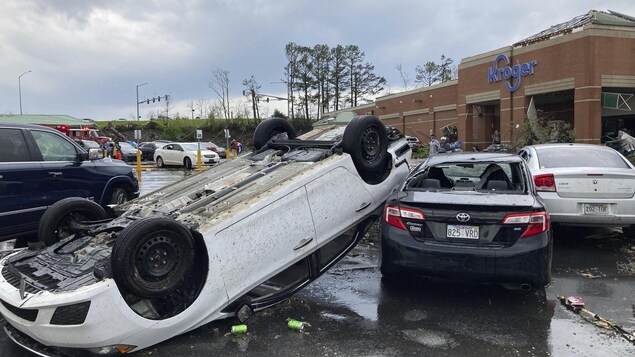 Une voiture renversé sur une autre voiture dans un stationnement