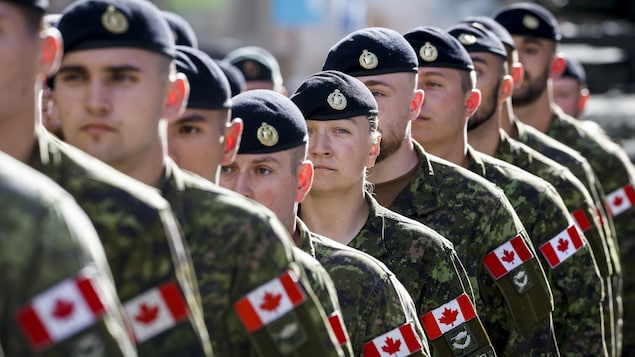 Des soldats canadiens debout les uns derrière les autres.