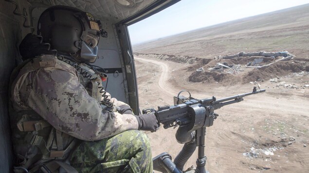 Un mitrailleur installé à bord d'un hélicoptère canadien.