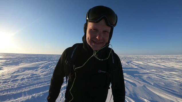 Un homme avec des lunettes de ski debout dans la neige.