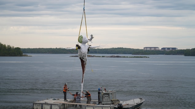 Des employés tentent de stabiliser la statue sur le lac Osisko.