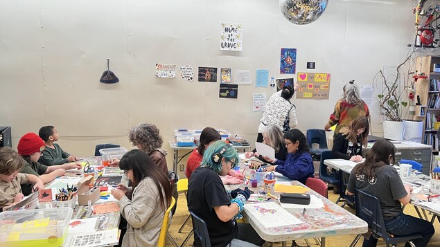 Des personnes assises à table créent des œuvres d’art.